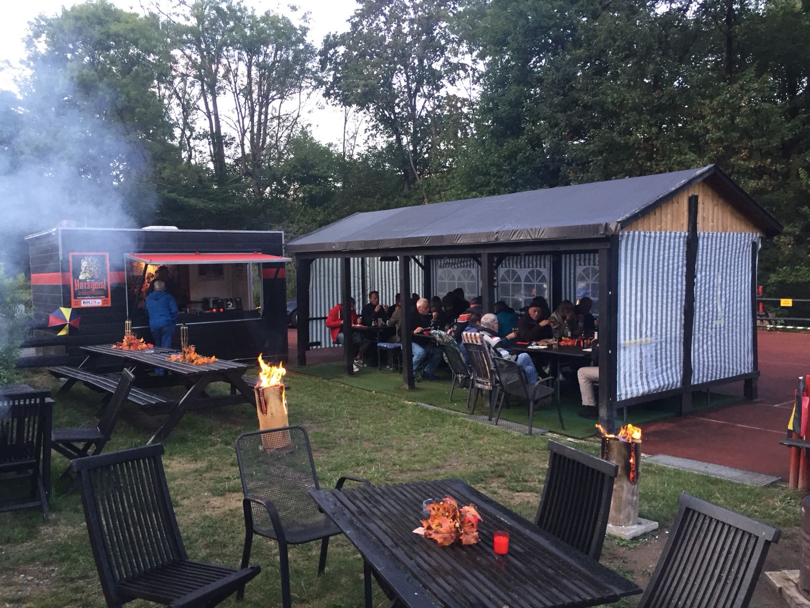 mennesker siddende omkring brændetønden